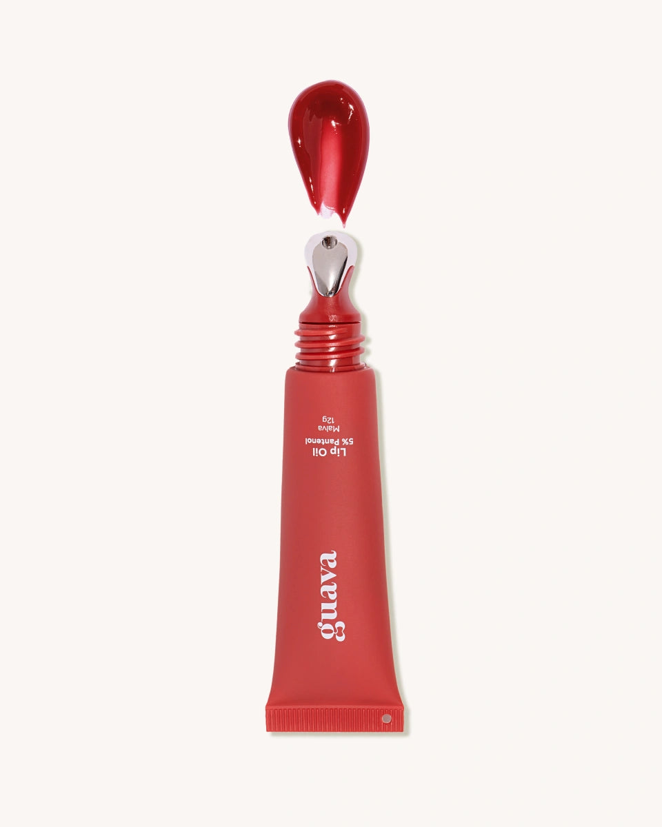 Lip Oil na cor Malva, com o aplicador levemente umedecido mostrando o tom rosado e a textura fluida do óleo labial hidratante.